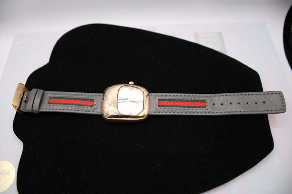 Luxury women's watch with a grey band and a stylish gold-tone case.