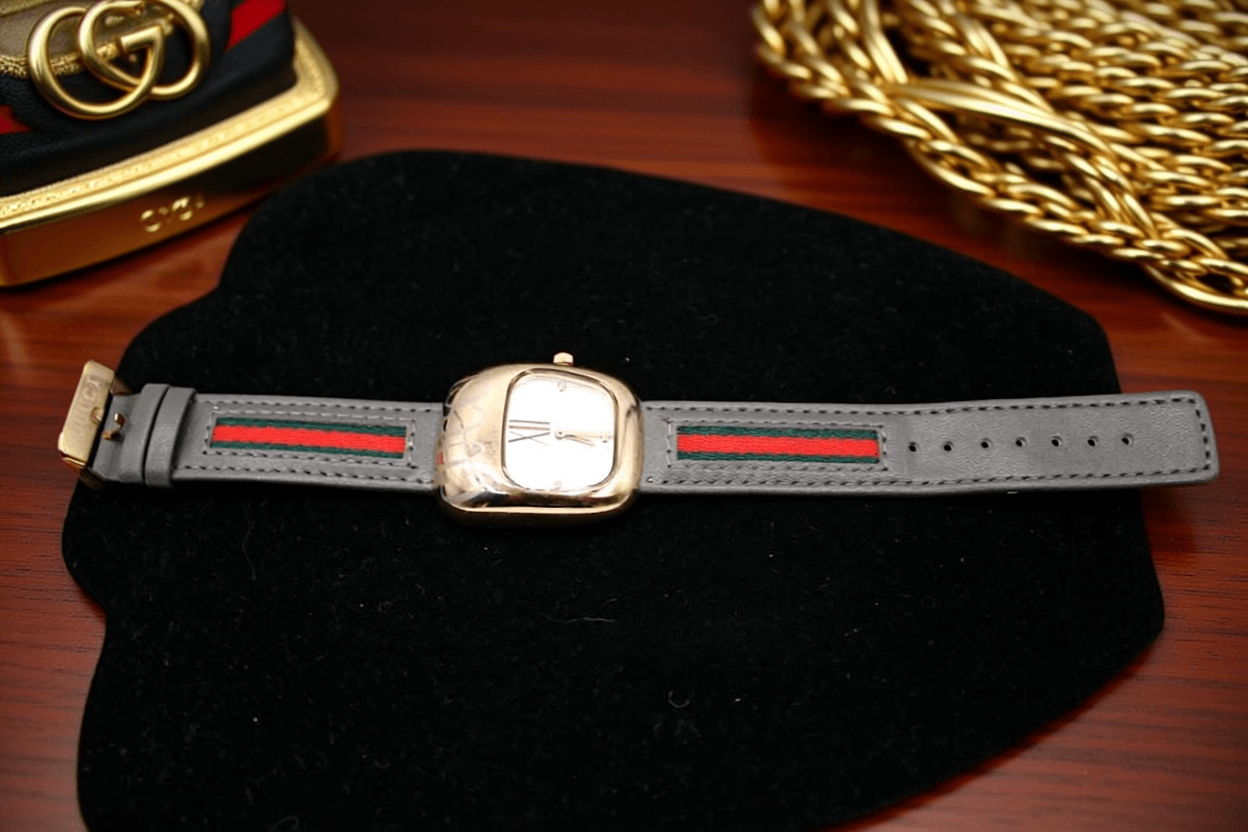 Luxury women's watch in grey with red and green stripes on the strap, showcasing elegant design and style.